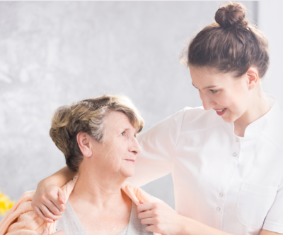 Image of a carer putting a cardigan around the client and looking at each other